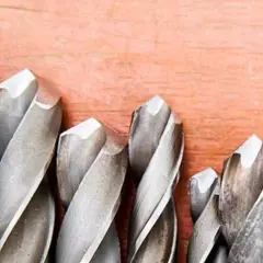 Ensemble de forets métalliques sur fond de bois. Apprenez comment mettre un foret dans une perceuse pour vos projets.