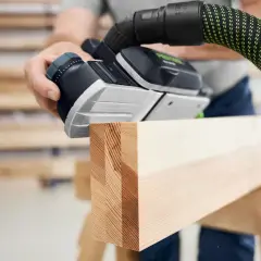 Main d'un artisan utilisant une raboteuse Festool pour lisser une pièce de bois.