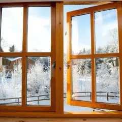 Une fenêtre en bois, prête à être poncée, s'ouvre sur un paysage hivernal enneigé.