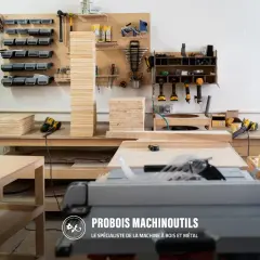 Un atelier bien organisé avec un rangement fait maison. Des outils, des planches de bois et une scie circulaire sont visibles.