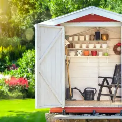 Aménagement abri de jardin : outils, pots de fleurs et chaise attendent le jardinier.