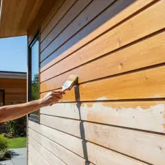 Application d'une lasure sur un bardage en bois. La lasure protège et embellit le bois, lui donnant une teinte chaude et naturelle.