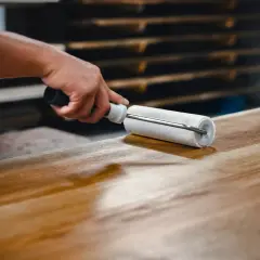 Application d'un vernis ou vitrificateur sur un plateau en bois avec un rouleau pour le protéger et le faire briller.