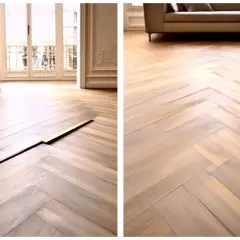 Un beau parquet en chevrons montre des signes de dilatation, le parquet qui gondole créant une fissure visible.