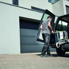 Un artisan charge son atelier mobile Festool dans son véhicule, prêt à intervenir sur un nouveau chantier.