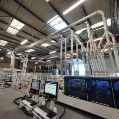 Un atelier moderne avec un système d'aspiration complexe, probablement pour un aspirateur Felder, capturant la poussière de machines à bois.