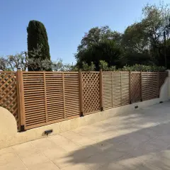 Une belle clôture en bois, parfaite pour un entretien facile et un style moderne. Elle délimite un espace extérieur avec des arbres en arrière-plan.