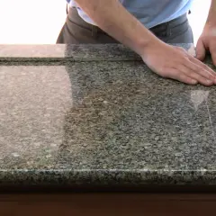 Main d'un homme posée sur un plan de travail en granit, prêt à le couper. Outil pour couper un plan de travail.