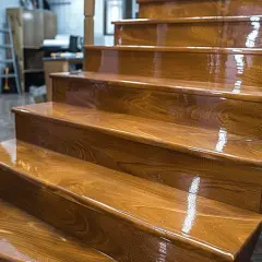 Escalier en bois neuf, dont les marches brillent après un vitrifier. La finition met en valeur le grain du bois.