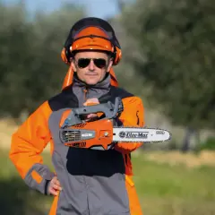 Un homme en tenue de protection, casque et lunettes, présente une tronçonneuse thermique. Il vous aide à choisir la meilleure.