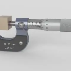 Un micromètre mesure un petit cube de bois. L'outil de précision affiche une mesure de 0 à 25 mm avec une précision de 0,01 mm.
