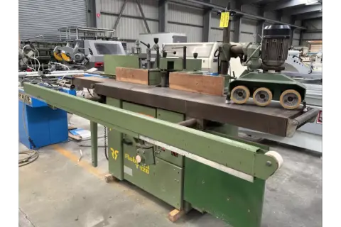 Une toupie tenonneuse verte, machine à bois industrielle, prête pour des travaux de menuiserie précis.