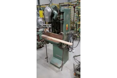 Machine à bois verte, une mortaiseuse à chaîne, avec une pièce de bois en position.