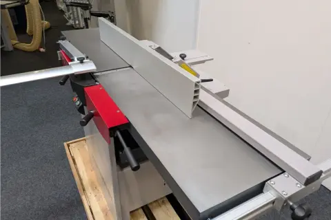 Détail d'une dégauchisseuse Hammer C3 41, machine à bois professionnelle avec son guide et ses poignées rouges.