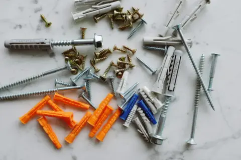 Diverses chevilles et vis, prêtes à mettre une cheville dans un mur placo.