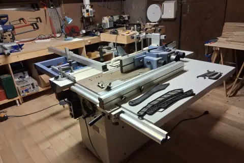 Un atelier de menuiserie avec une machine combinée Felder KF 500, des outils et des planches de bois.