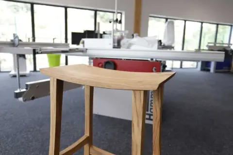 Tabouret en bois, œuvre d'un artisan utilisant un combiné bois Hammer. Lignes épurées, bois naturel.
