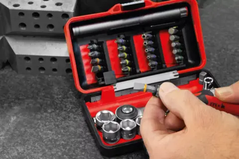 Une main insère un embout dans un cliquet rouge. Ce coffret d'embouts et douilles est un exemple de marque outillage français, conçu pour la précision.