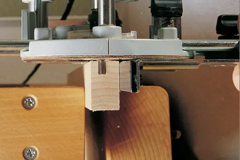 Utilisation d'un gabarit rainure défonceuse pour créer une entaille précise dans une pièce de bois.