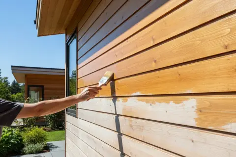 Application d'une lasure sur un bardage en bois. La lasure protège et embellit le bois, lui donnant une teinte chaude et naturelle.