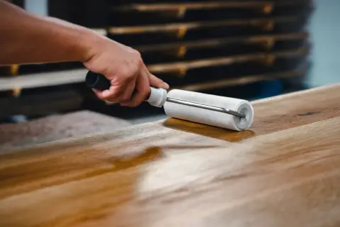 Application d'un vernis ou vitrificateur sur un plateau en bois avec un rouleau pour le protéger et le faire briller.