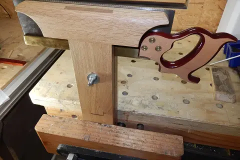 Un guide en bois et laiton aide à comment affûter une lame de banc de scie. La lame est tenue dans un étau.