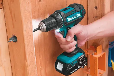 Comment reconnaître Makita Pro : une perceuse sans fil turquoise et noire de Makita est utilisée pour visser dans du bois.