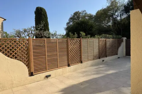 Une belle clôture en bois, parfaite pour un entretien facile et un style moderne. Elle délimite un espace extérieur avec des arbres en arrière-plan.