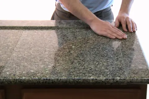 Main d'un homme posée sur un plan de travail en granit, prêt à le couper. Outil pour couper un plan de travail.
