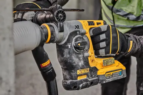 Main d'un ouvrier tenant un marteau-piqueur DeWalt origine, prêt à travailler sur un chantier.