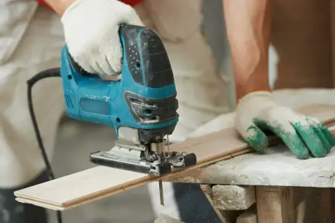 Main tenant utilise une scie sauteuse pour apprendre comment couper droit.