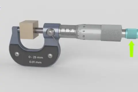 Un micromètre mesure un petit cube de bois. L'outil de précision affiche une mesure de 0 à 25 mm avec une précision de 0,01 mm.