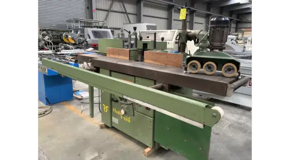 Une toupie tenonneuse verte, machine à bois industrielle, prête pour des travaux de menuiserie précis.