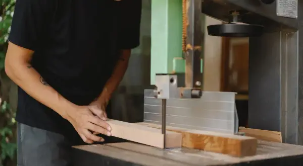 Un artisan utilise une scie stationnaire pour découper une pièce de bois.