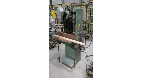 Machine à bois verte, une mortaiseuse à chaîne, avec une pièce de bois en position.