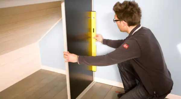 Un homme utilise un niveau pour fabriquer un placard sous pente de toit.