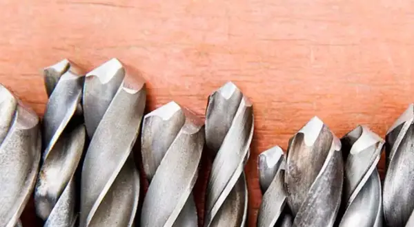 Ensemble de forets métalliques sur fond de bois. Apprenez comment mettre un foret dans une perceuse pour vos projets.