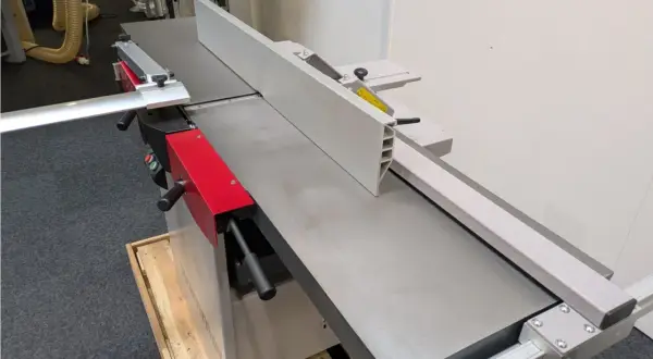 Détail d'une dégauchisseuse Hammer C3 41, machine à bois professionnelle avec son guide et ses poignées rouges.