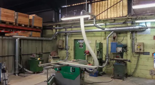Atelier de menuiserie avec scie, dégauchisseuse, et une aspiration atelier bois occasion pour un environnement de travail propre.