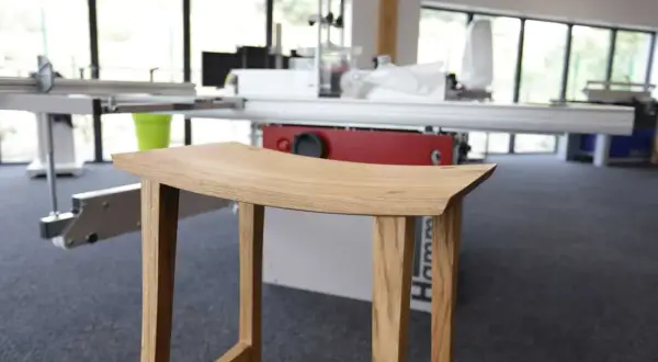 Tabouret en bois, œuvre d'un artisan utilisant un combiné bois Hammer. Lignes épurées, bois naturel.
