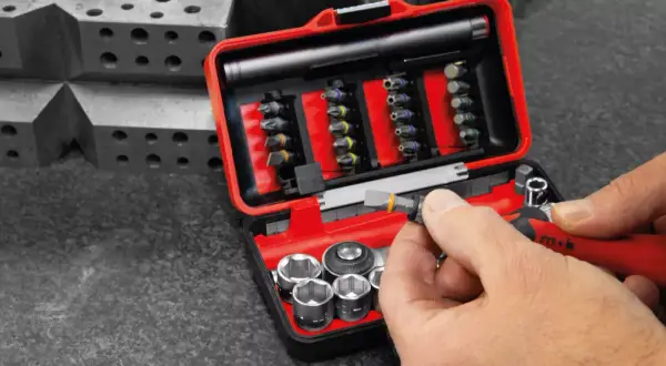 Une main insère un embout dans un cliquet rouge. Ce coffret d'embouts et douilles est un exemple de marque outillage français, conçu pour la précision.