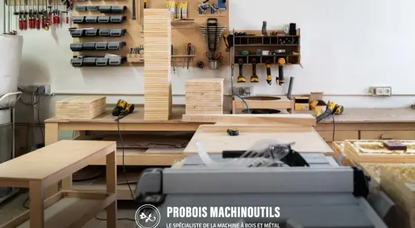 Un atelier bien organisé avec un rangement fait maison. Des outils, des planches de bois et une scie circulaire sont visibles.