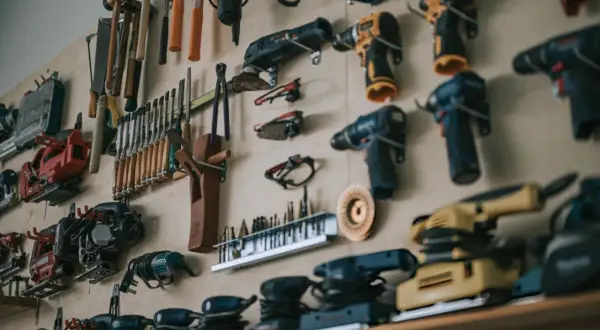 Un mur rempli d'outils pour travailler le bois : perceuses, ponceuses, scies sauteuses, ciseaux, marteaux et autres accessoires essentiels pour tout artisan.