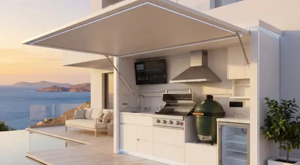 Une cuisine d'été fait maison moderne avec barbecue, évier, frigo et TV, surplombant la mer et une piscine.