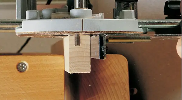 Utilisation d'un gabarit rainure défonceuse pour créer une entaille précise dans une pièce de bois.