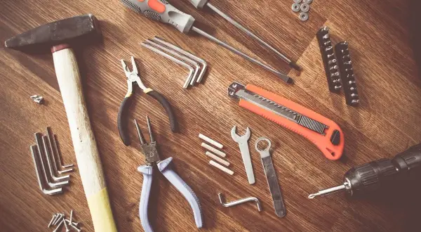 Un marteau, des tournevis, des pinces, une lame rétractable, des clés Allen et une perceuse : tous ces nom d'outils de bricolage sont prêts pour un projet.