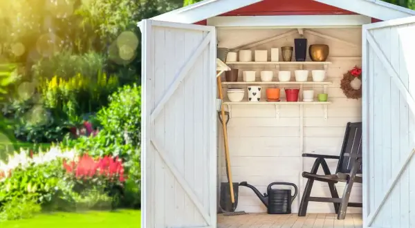 Aménagement abri de jardin : outils, pots de fleurs et chaise attendent le jardinier.