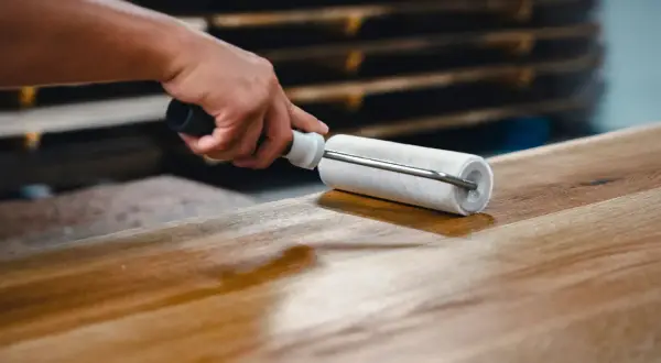 Application d'un vernis ou vitrificateur sur un plateau en bois avec un rouleau pour le protéger et le faire briller.