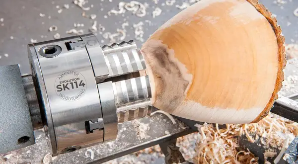 Mandrin de tour à bois fait maison, prêt à façonner un objet en bois. Copeaux de bois éparpillés.