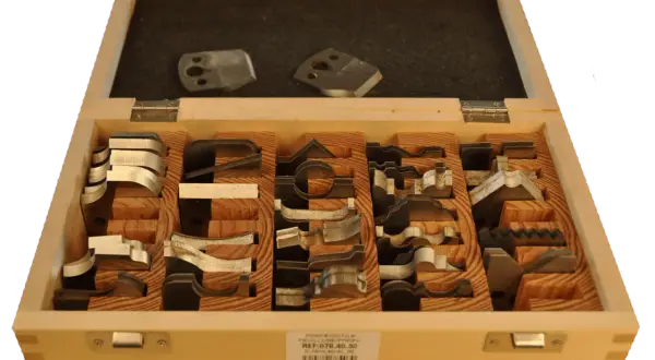 Boîte en bois contenant divers fers de toupie pour le travail du bois.